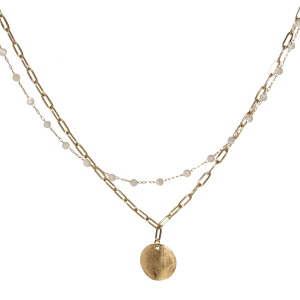 Collier double rangs composé d'une chaîne de 39 cm de long en acier doré avec des perles de couleur blanche, ainsi qu'une chaîne de 40 cm de long avec une pastille ronde difforme en acier doré. Fermoir mousqueton avec 5 cm de rallonge.