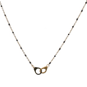 Collier composé d'une chaîne avec une paire de menottes en acier doré et de perles en émail de couleur noire. Fermoir mousqueton avec 5 cm de rallonge.