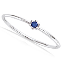 Bague en argent 925/000 rhodié surmontée d'une pierre synthétique de couleur bleue sertie griffes.