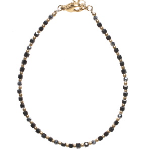 Bracelet composé d'une chaîne de perles en acier doré et de perles rondes et cubiques de couleur noire. Fermoir mousqueton avec 3 cm de rallonge.