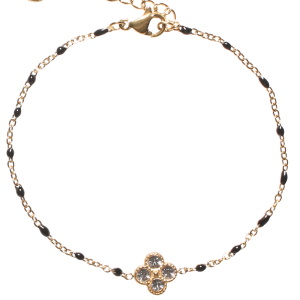 Bracelet composé d'une chaîne en acier doré, de perles en émail de couleur noir et d'un trèfle à quatre feuilles sertis de strass. Fermoir mousqueton avec 3 cm de rallonge.