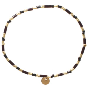 Bracelet élastique composé de perles cylindriques en acier doré et perles cylindriques de couleur noire.