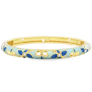 Ce magnifique bracelet jonc en métal doré allie le charme du style vintage au raffinement de l'artisanat d'art. Conçu avec une ouverture à charnière pratique, il épouse délicatement le poignet pour une touche d'élégance intemporelle. La surface extérieure est ornée d'un superbe travail d'émaillage. Un fond bleu ciel doux et texturé met en valeur des motifs floraux contrastés d'un bleu roi profond. Les fleurs en émail bleu sont rehaussées en leur centre par de petits éclats brillants, apportant une touche de lumière subtile à chaque mouvement. Des volutes et des arabesques dorées viennent parfaire ce décor poétique.