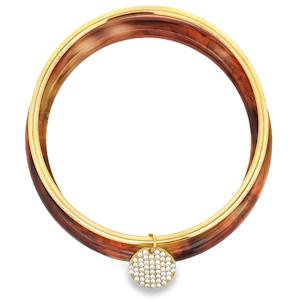 Rehaussez votre style avec cet ensemble de bracelets joncs captivants. Sa structure en acier doré offre une chaleur rayonnante, sublimée par un pendentif orné de cristaux scintillants. La coupe cabochon de ces cristaux révèle leur éclat subtil, ajoutant une touche de sophistication discrète à cette pièce intemporelle.