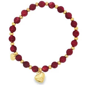 Bracelet élastique de perles captivant, rehaussé d'acier doré éclatant. Chaque perle rouge, taillée en cabochon arrondi, possède un éclat translucide. La clarté VS des perles est mise en valeur par un poli et une symétrie impeccables. Un bijou vibrant d'élégance, où l'éclat de l'acier doré sublime la profondeur du rouge.