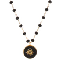 Collier composé d'une chaîne en acier doré avec perles de pierres de couleur noire et d'un pendentif rond au motif d'étoile en acier doré pavé d'émail de couleur noire surmonté d'un cristal serti clos. Fermoir mousqueton avec 5 cm de rallonge.