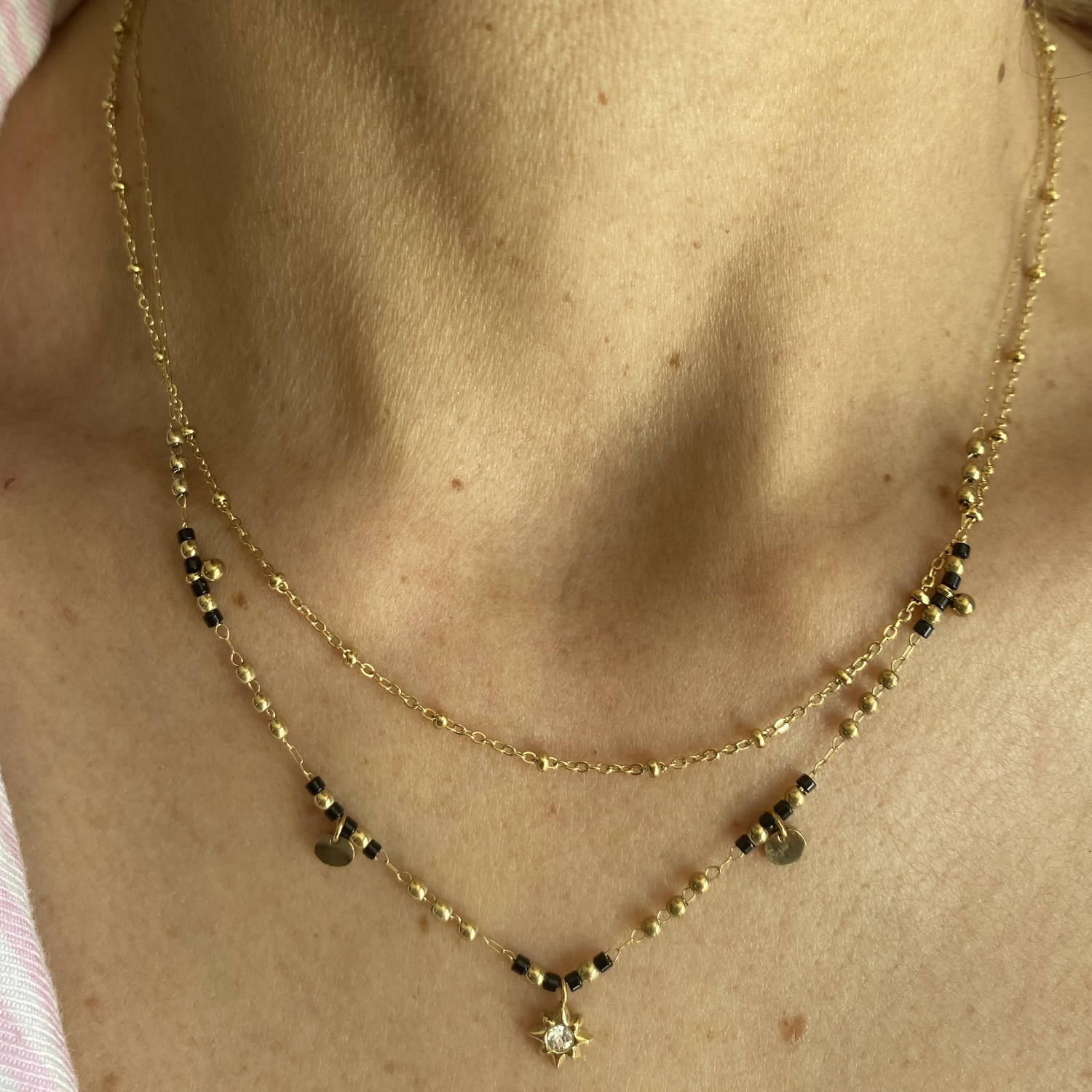 Collier composé d'une chaîne de 39 cm de long en acier doré, ainsi qu'une chaîne de 41 cm de long avec perles et deux pampilles rondes en acier doré, de perles de couleur noire et d'un pendentif étoile sertie d'un cristal.<br/>Fermoir mousqueton avec 5 cm de rallonge. Etoile Multirangs Perle Strass Adolescent Adulte Femme Fille Indémodable Nature Collier composé d'une chaîne de 39 cm de long en acier doré, ainsi qu'une chaîne de 41 cm de long avec perles et deux pampilles rondes en acier doré, de perles de couleur noire et d'un pendentif étoile sertie d'un cristal.<br/>Fermoir mousqueton avec 5 cm de rallonge. Etoile Multirangs Perle Strass Adolescent Adulte Femme Fille Indémodable Nature
