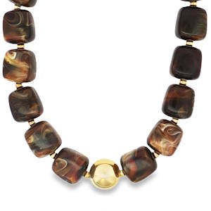 Ce collier de perles, composé de perles de forme carrée aux nuances riches de brun et de crème, est un bijou unique en son genre. Accentué par des perles dorées, ce collier apportera une touche d'élégance à votre style. Fermoir mousqueton avec 5 cm de rallonge.