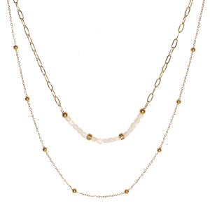 Collier double rangs composé d'une chaîne de 39 cm de long en acier doré et de perles de nacre, ainsi qu'une chaîne de 46 cm de long avec boules en acier doré. Fermoir mousqueton avec 5 cm de rallonge.