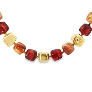 Ce collier de perles met en valeur une esthétique audacieuse avec ses perles cubiques alternant des teintes chaudes de rouge et d'ambre et des accents dorés éclatants. Chaque perle est soigneusement enfilée, créant un contraste visuel attrayant qui attire le regard. Un bijou contemporain qui ajoute une touche d'originalité à toute tenue. Mousqueton avec 5 cm de rallonge.
