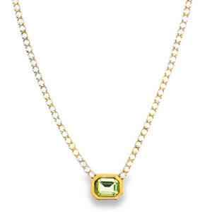 Ce collier pendentif exquis en acier doré est orné d'un cristal vert de taille émeraude à degrés. Sa clarté impeccable et sa symétrie confèrent un éclat exceptionnel. Un design délicat qui offre une composition charmante, idéale pour ajouter une touche d'élégance discrète à votre collection de bijoux.