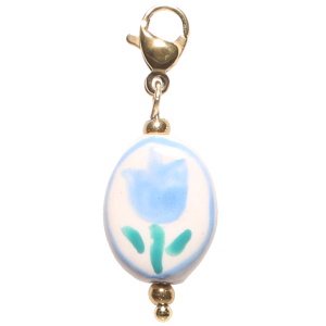 Charm's avec mousqueton en acier doré et une pastille ovale représentant une fleur.