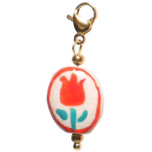 Charm's avec mousqueton en acier doré et une pastille ovale représentant une fleur.