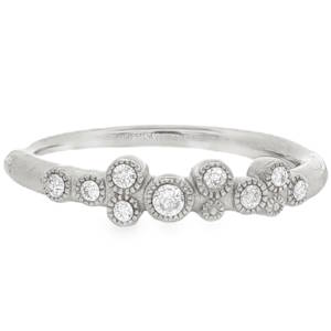 Cette bague en acier inoxydable se distingue par son anneau au fini brossé et légèrement texturé, lui donnant un aspect brut et moderne. L'élément central est une composition asymétrique de plusieurs petits cercles sertis, rappelant des bulles ou des constellations. Elle est ornée de multiples cristaux de tailles variées, qui apportent un éclat lumineux à chaque mouvement de la main.