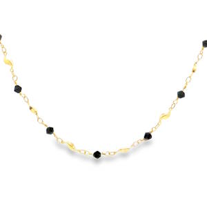 Laissez-vous séduire par ce magnifique collier qui allie la chaleur du plaqué or 18 carats à l'intensité mystérieuse de perles noires. Conçu pour la femme moderne qui apprécie la finesse, ce bijou est une pièce maîtresse de délicatesse. Ce collier se distingue par son alternance harmonieuse de textures et de formes.  Des perles noires taillées avec précision qui capturent la lumière à chaque mouvement et de délicates pampilles dorées en forme de navettes ou de feuilles stylisées, apportant une touche naturelle et fluide à l'ensemble.
