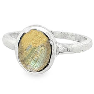 Cette élégante bague se distingue par son alliance harmonieuse entre la sobriété de l'argent et la beauté naturelle de sa pierre centrale. Conçue avec un style intemporel et une touche bohème-chic, elle met en valeur un travail artisanal soigné. Une pierre naturelle taillée en cabochon ovale présente des teintes douces et changeantes de doré, de beige et d'aurore boréale, rappelant les reflets irisés de la labradorite dorée. Ses inclusions naturelles captent la lumière sous différents angles, rendant chaque pièce unique.